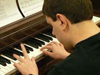 Kyle playing a song on a piano during a christmas sing-a-long